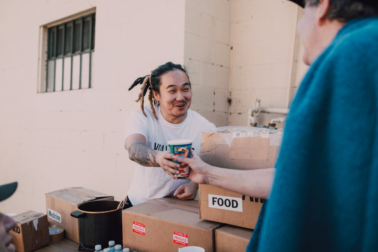 A volunteer handing out food and drinks at a charity event to support community causes.